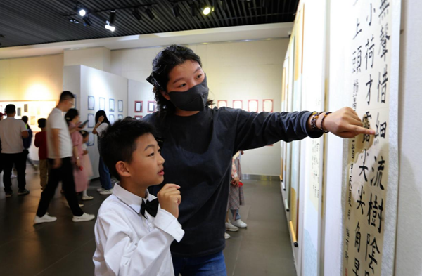 孩子在现场观摩学习书法作品 （吴帆 摄）